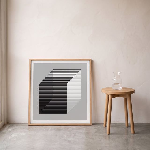 Geo Cube B&W framed leaning against the wall on a concrete floor – art print by Marcio Pontes