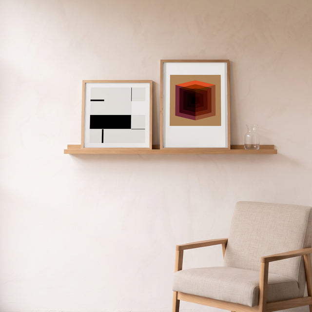 Cube Grid White framed on an oak picture shelf beside a linen armchair – art print by Marcio Pontes