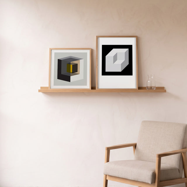 Cube Yellow Inside framed on an oak picture shelf beside a linen armchair – art print by Marcio Pontes