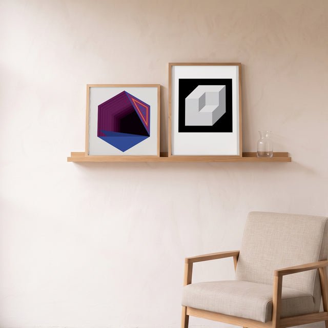 Hexa 6 framed on an oak picture shelf beside a linen armchair – art print by Marcio Pontes