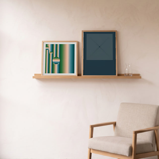 Retrocosmos Green framed on an oak picture shelf beside a linen armchair – art print by Marcio Pontes