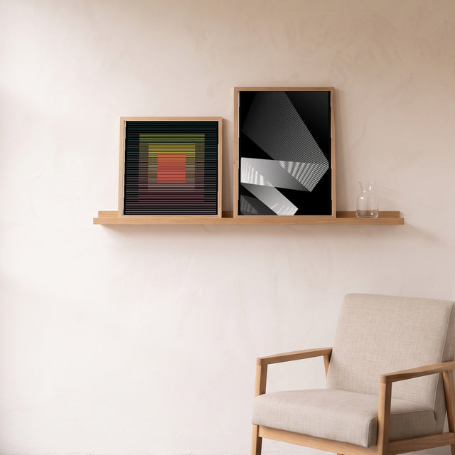 White Lines 1 framed on an oak picture shelf beside a linen armchair – art print by Marcio Pontes